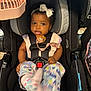 baby, car_seat, child, infant, headband, bow, pacifier, colorful_clothing, straps, black_car_seat, pink_fan, baby_clothes, seatbelt, playful_expression, indoor, closeup, cute, child_safety, infant_fashion, baby_feet