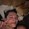 Batman is registered to the contest to win money with this photo: person, dog, face, smile, peace_sign, indoor, closeup, resting, brown_dog, casual, tattoo, piercing, black_shirt, friendly, companion, pet, relaxing, portrait, skin, human