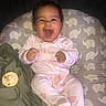 Kaia is registered to the contest to win money with this photo: baby, blanket, child, cozy, cushion, cute, elephant_pattern, face, happy, indoors, infant, laughing, pacifier, person, pink_pajamas, playful, sitting, smiling, soft, young