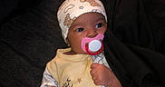 Kaia is registered to the contest to win money with this photo: baby, bear_pattern, blanket, child, clothing, comfort, cute, dark_background, face, hand, hat, indoors, infant, lying_down, newborn, pacifier, pajamas, sleep, sleepwear, soft_toys