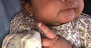 Kaia is registered to the contest to win money with this photo: baby, infant, face, hand, mitten, clothing, floral_pattern, cute, portrait, skin, cheeks, person, newborn, expression, indoors, closeup, child, soft, sleeve, young
