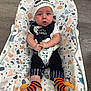 baby, infant, child, halloween, hat, bib, socks, orange, black, white, striped_socks, baby_seat, patterned_seat, floor, wood_floor, clothing, cute, sitting, face, person