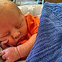 baby, newborn, sleeping, blanket, orange_clothing, hand, face, peaceful, resting, infant, cute, skin, closeup, portrait, cozy, soft, indoors, star_pattern, pillow, child