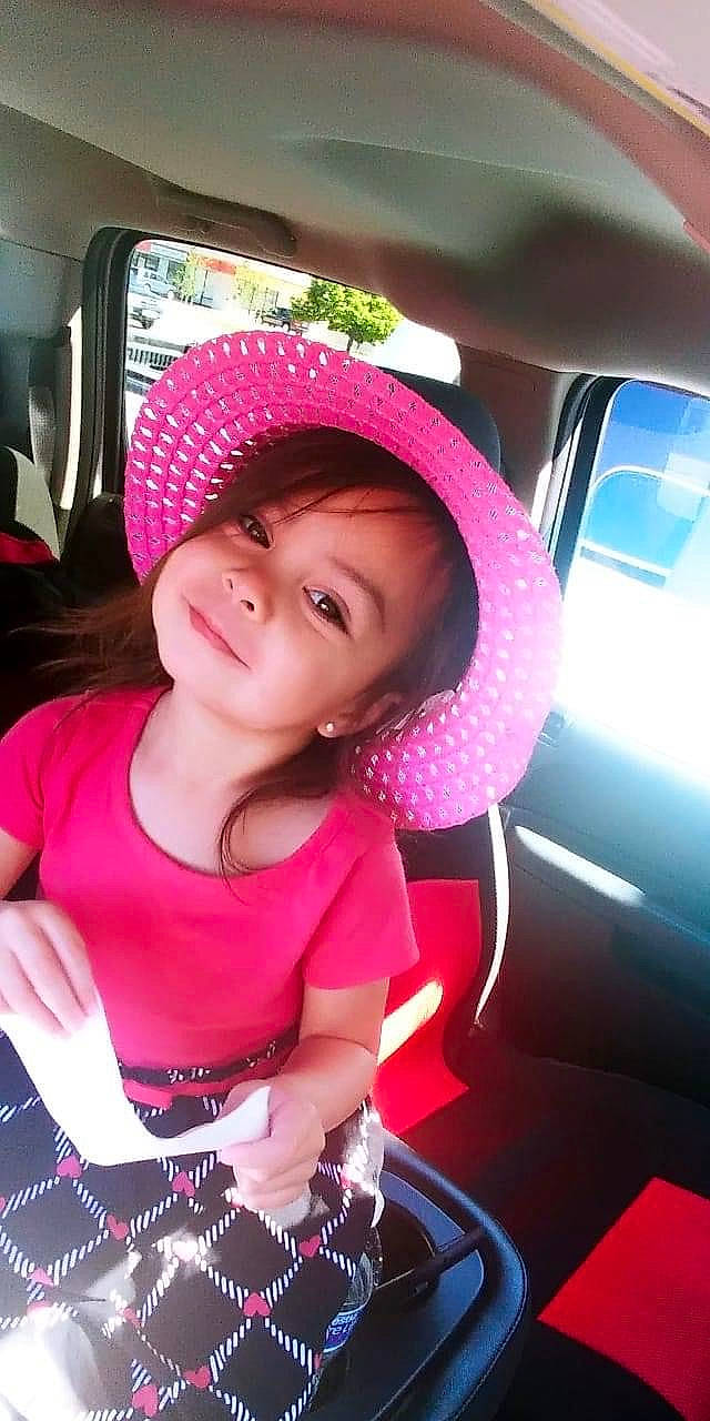 Nathalie is registered to the contest to win money with this photo: car, car_seat, child, cool, hat, headgear, joy, person, pink, selfie, smile, steering_wheel, sun_hat, toddler, vehicle