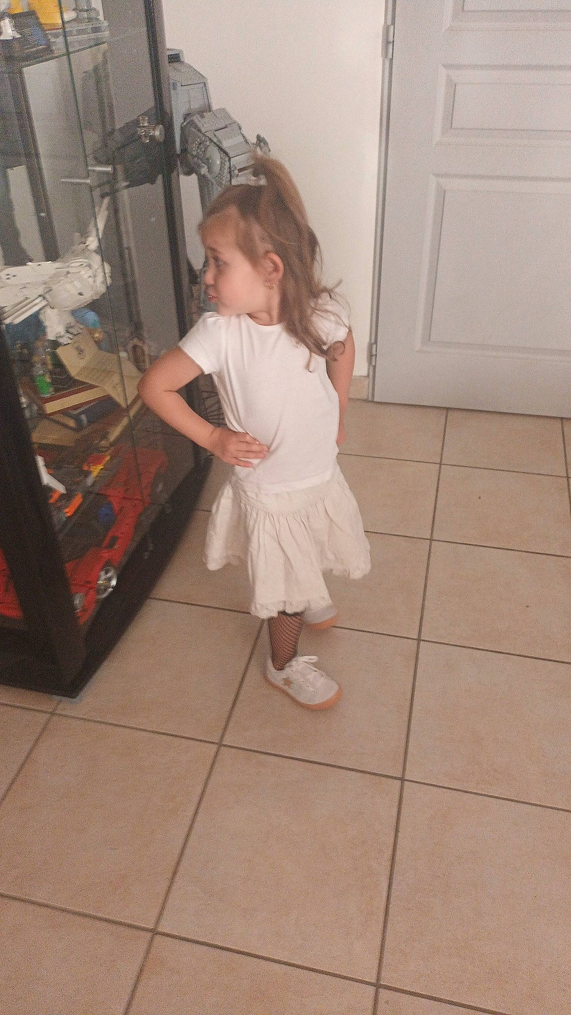 Eleana participe au concours pour gagner de l'argent avec cette photo : baby_toddler_clothing, child, door, drawer, dress, floor, flooring, foot, fun, hardwood, human_leg, knee, laundry_room, leg, long_hair, person, sandal, sock, toddler, wood