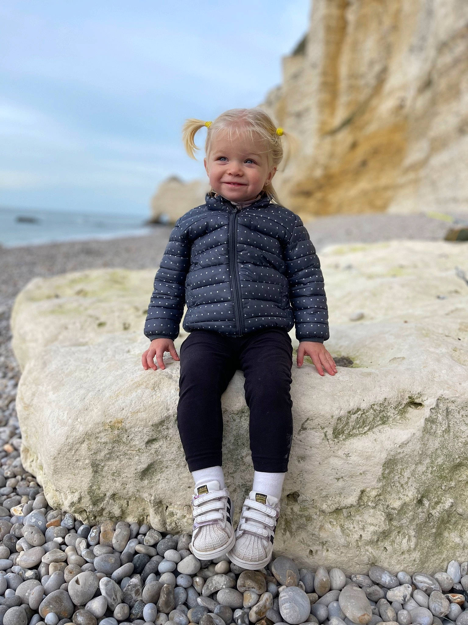 Eleonora participe au concours pour gagner de l'argent avec cette photo : bedrock, coast, eye, flash_photography, geology, happy, joy, landscape, leg, pattern, people_in_nature, person, rock, sand, sitting, sky, sleeve, smile, t_shirt, toddler
