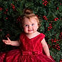 background, blue_eyes, bow, celebration, child, christmas, curly_hair, cute, festive, happy, holiday, lace, pine_branches, portrait, red_berries, red_dress, sitting, smile, toddler, topknot