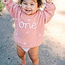 toddler, child, baby, smiling, holding_hands, sweater, pink_clothing, outdoor, walking, barefoot, hair_clip, sunlight, concrete, cute, happy, person, young_child, early_walking, portrait, daylight