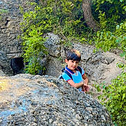 Muhamad Ibrahim participe au concours pour gagner de l'argent avec cette photo : child, boy, rock, forest, nature, greenery, trees, outdoor, adventure, smiling, curious, daylight, backpack, plants, leaves, young, exploration, casual_clothing, natural_light, scenery