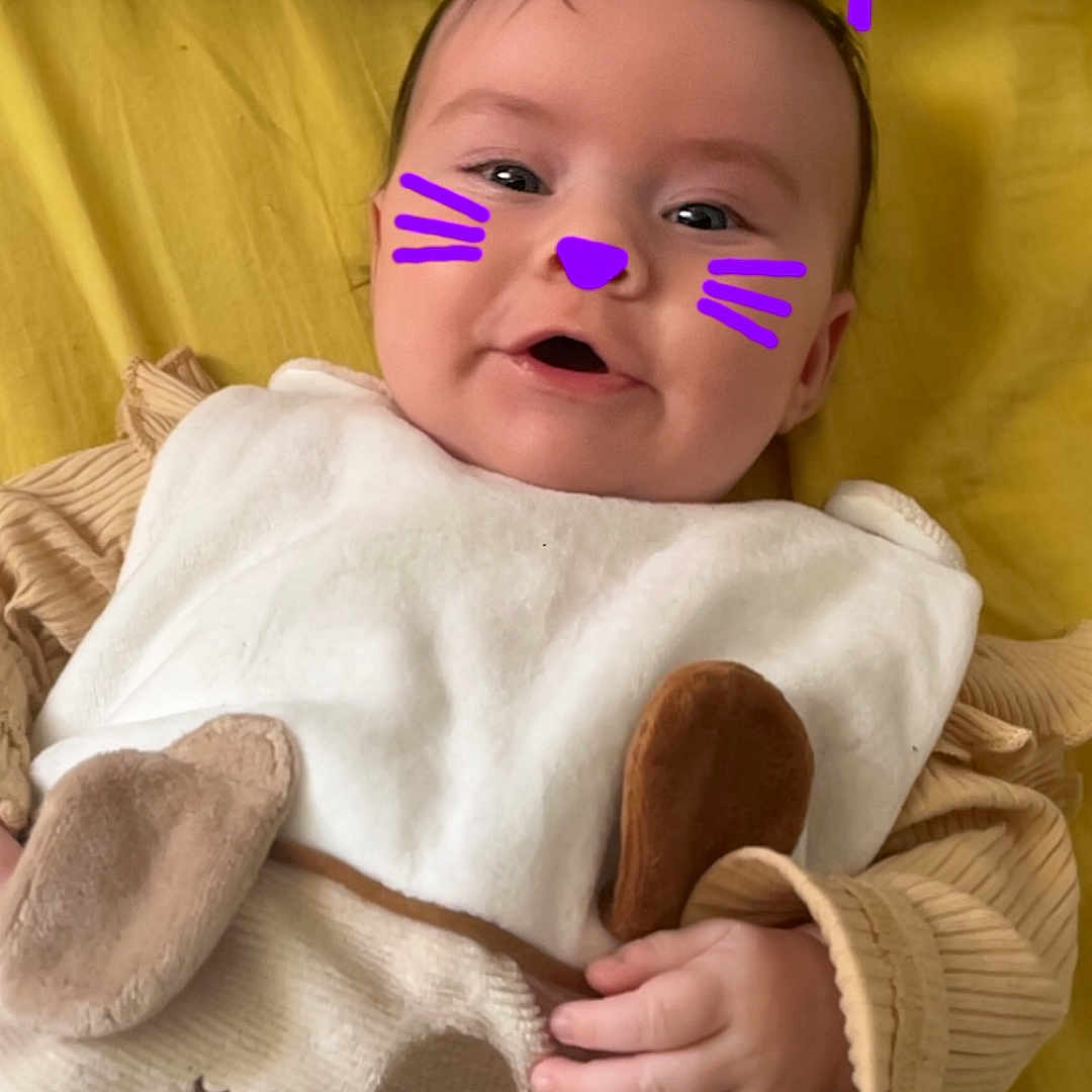 Angëlya participe au concours pour gagner de l'argent avec cette photo : baby, bed, blanket, cat_ears, child, clothing, cozy, cute, digital_overlay, face_paint, hand, happy, indoors, infant, portrait, purple, smiling, soft_toys, whiskers, yellow