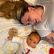 Waylon is registered to the contest to win money with this photo: baby, infant, adult, mother, smiling, lying_down, blanket, conversation_hearts, candy, milestone, two_months, tattoo, earring, nose_ring, portrait, white_shirt, wooden_sign, celebration, bedroom, cute