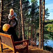Matthew joined the competition — help win amazing prizes! child, toddler, adult, bench, forest, trees, lake, outdoor, sunlight, nature, happy, playful, smiling, person, wood, sky, pine_tree, daytime, leisure, family