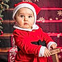 baby, child, santa_hat, red_clothing, holiday, christmas, festive, portrait, indoors, wooden_stool, cute, holiday_decor, face, expression, winter_clothing, festive_background, holiday_spirit, young_child, seasonal, sitting