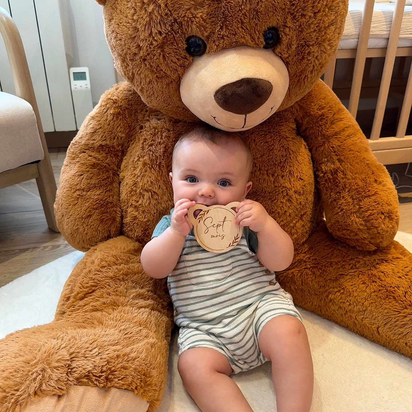 Louis a rejoint le concours — aidez-le/la à gagner de superbes lots ! baby, baby_clothes, carpet, child, childrens_room, cute, floor_rug, furniture, happy, indoor, infant, nursery, plush_toy, portrait, smiling, soft_toy, striped_outfit, teddy_bear, toy, wooden_sign