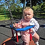 baby, child, swing, playground, outdoor, park, sunny, trees, fence, clothing, white_socks, curious, puzzled_expression, seat, metal_chains, red, blue, person, infant, daytime