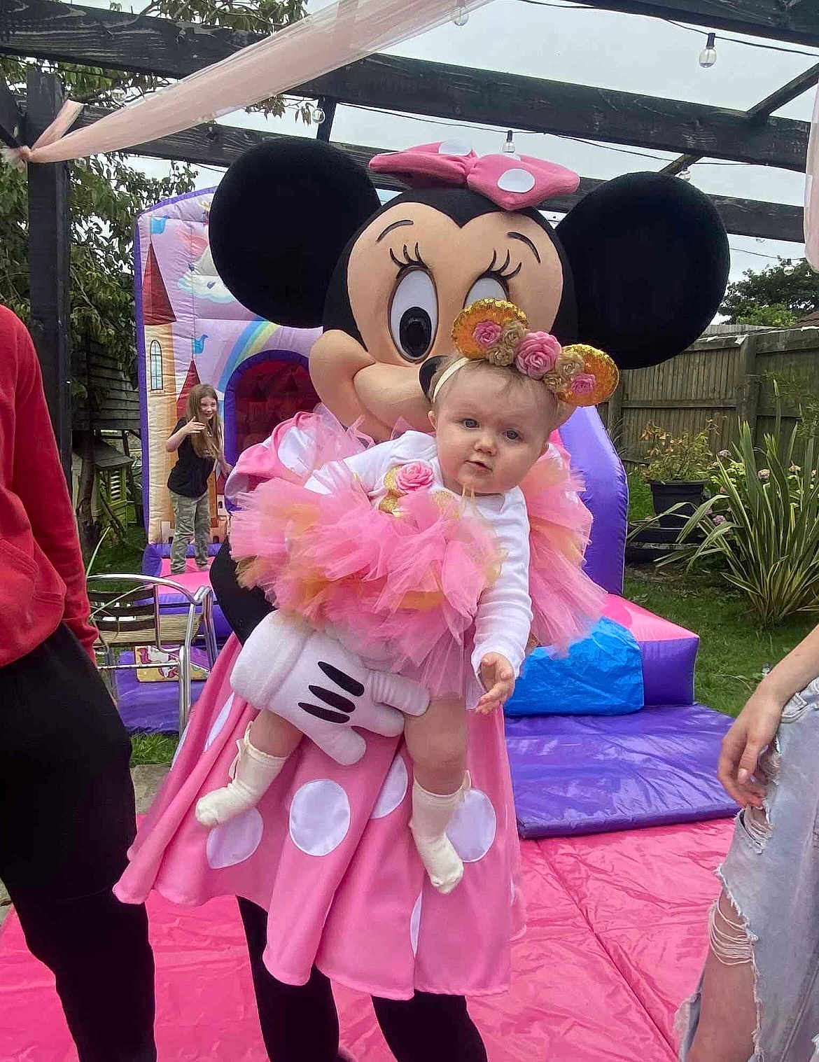 Harper-Grace is registered to the contest to win money with this photo: baby, tutu, pink, flower_crown, minnie_mouse, costume, person, outdoor, party, bouncy_castle, child, grass, fence, play, celebration, fun, cute, headband, sock, event