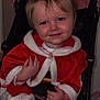 Harper-Grace is registered to the contest to win money with this photo: toddler, child, stroller, red_cape, bow, smile, face, hands, seatbelt, holiday_outfit, portrait, indoor, cute, blond_hair, topknot, flash_red_eye, baby_clothes, cozy, sitting, closeup