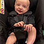 Arthur is registered to the contest to win money with this photo: baby, black_clothing, car_accessory, car_seat, child, cute, face, footwear, hands, happy, head, indoors, infant, legs, person, portrait, safety, seatbelt, smiling, young_child
