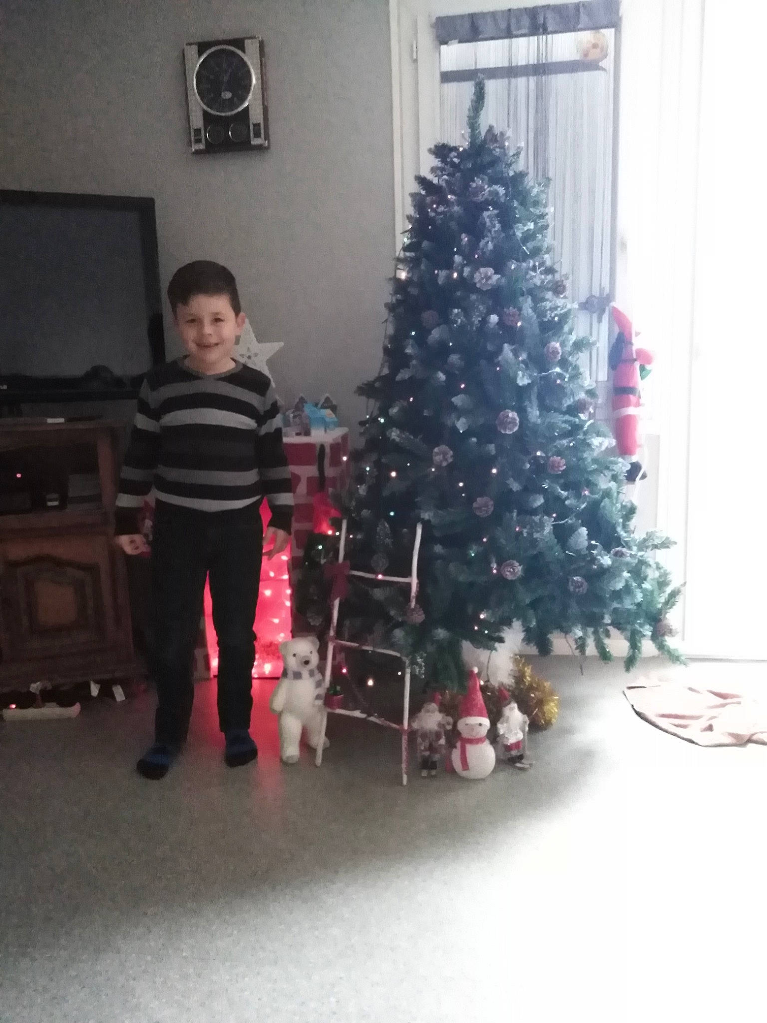 Mayron a rejoint le concours — aidez-le/la à gagner de superbes lots ! christmas, christmas_decoration, christmas_eve, christmas_ornament, christmas_tree, conifer, event, evergreen, flooring, fun, holiday, holiday_ornament, joy, living_room, ornament, person, room, sitting, standing, toddler