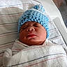 newborn, baby, infant, sleeping, knitted_hat, blue_hat, swaddled, blanket, hospital, bassinet, portrait, face, closed_eyes, peaceful, indoors, stripes, textile, bedding, nursery, photography