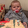 Alba participe au concours pour gagner de l'argent avec cette photo : baby, pacifier, gray_hoodie, chair, beige_leather, wrapping_paper, red_cars, christmas_trees, holiday_theme, cute, infant, smiling, indoors, festive, gift, present, child, person, cozy, seated