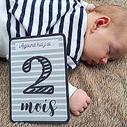 Noah a rejoint le concours — aidez-le/la à gagner de superbes lots ! baby, sleeping, striped_clothing, denim, carpet, milestone_card, age_card, hand, face, infant, newborn, side_view, resting, cute, child, soft_texture, indoor, closeup, portrait, peaceful