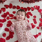 Athena joined the competition — help win amazing prizes! baby, infant, child, heart_pattern, red_hearts, petals, blanket, smiling, cute, happy, lying_down, celebration, valentines, decorations, soft_lighting, portrait, indoors, clothing, face, hands