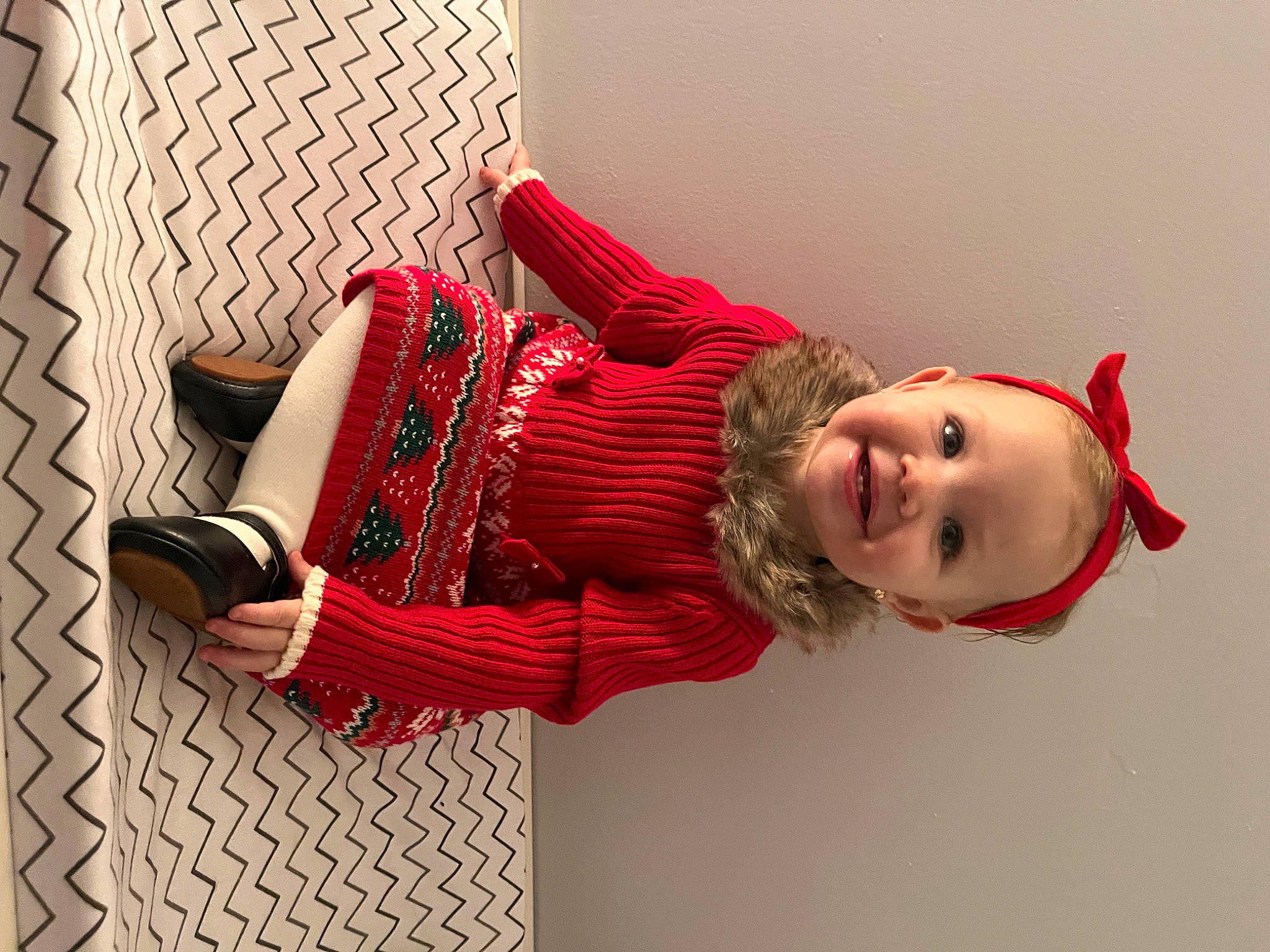 Harper is registered to the contest to win money with this photo: child, dress, fashion_design, flooring, happy, human_leg, joy, knee, magenta, pattern, person, pink, plaid, room, sitting, sleeve, smile, textile, thigh, toddler