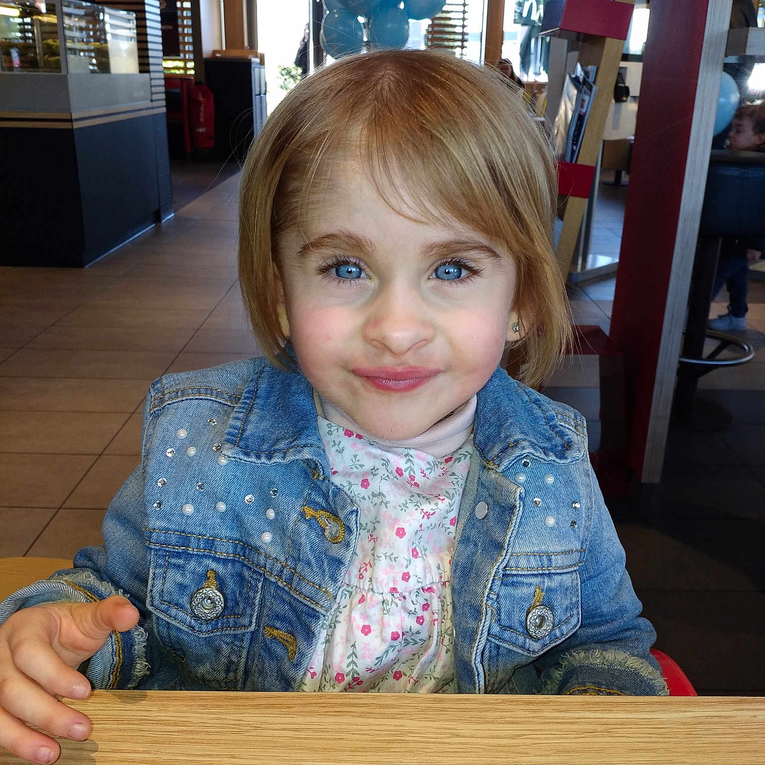 Lana a rejoint le concours — aidez-le/la à gagner de superbes lots ! blond, child, floor, flooring, fun, hair, iris, person, sitting, smile, table, toddler, vacation, wood