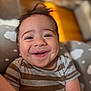 baby, smiling, infant, striped_shirt, dimples, face, head, happy, child, cushion, cloud_pattern, toddler, cute, portrait, indoors, skin, hair, person, clothing, closeup