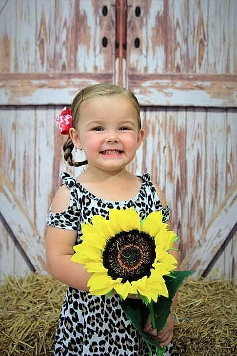 Karleigh joined the competition — help win amazing prizes! baby, baby_toddler_clothing, bouquet, child, child_model, cut_flowers, dress, fashion_accessory, flower, gerbera, happy, joy, pattern, person, photography, plant, smile, sunflower, toddler, yellow