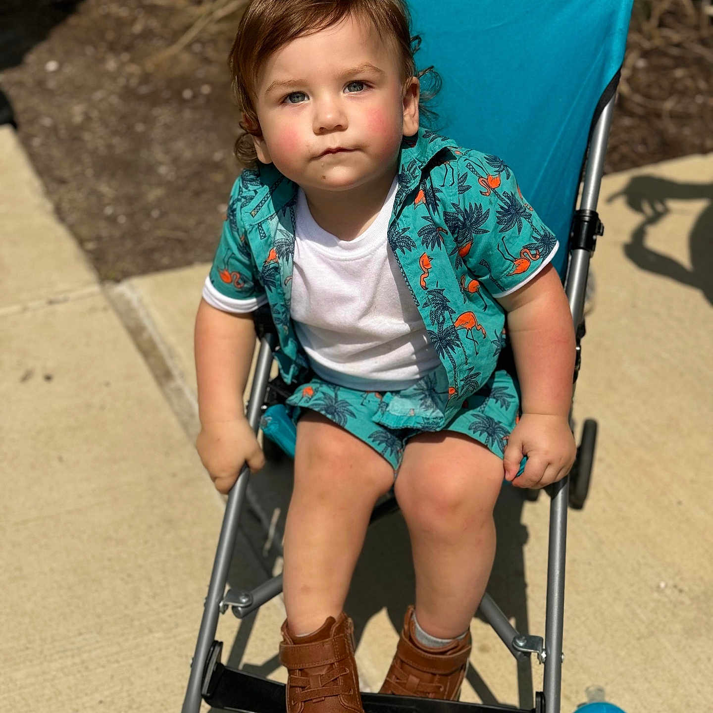 Jaxson is registered to the contest to win money with this photo: baby, city, clothing, face, footwear, furniture, head, jeans, machine, pants, person, photography, portrait, road, shoe, shorts, sitting, street, stroller, wheel