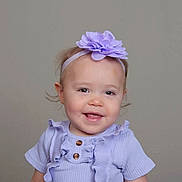 Odessa is registered to the contest to win money with this photo: baby, child, girl, headband, flower, smile, portrait, clothing, purple, ruffles, cute, happy, face, infant, young_child, studio, neutral_background, headwear, fashion, toddler