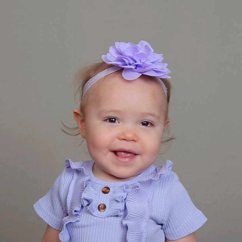 Odessa is registered to the contest to win money with this photo: baby, child, clothing, cute, face, fashion, flower, girl, happy, headband, headwear, infant, neutral_background, portrait, purple, ruffles, smile, studio, toddler, young_child