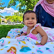 Zainab Saleha is registered to the contest to win money with this photo: baby, child, smile, blanket, grass, outdoor, park, person, woman, scarf, blue_clothing, pink_scarf, sunny, daylight, nature, trees, happy, cute, infant, portrait