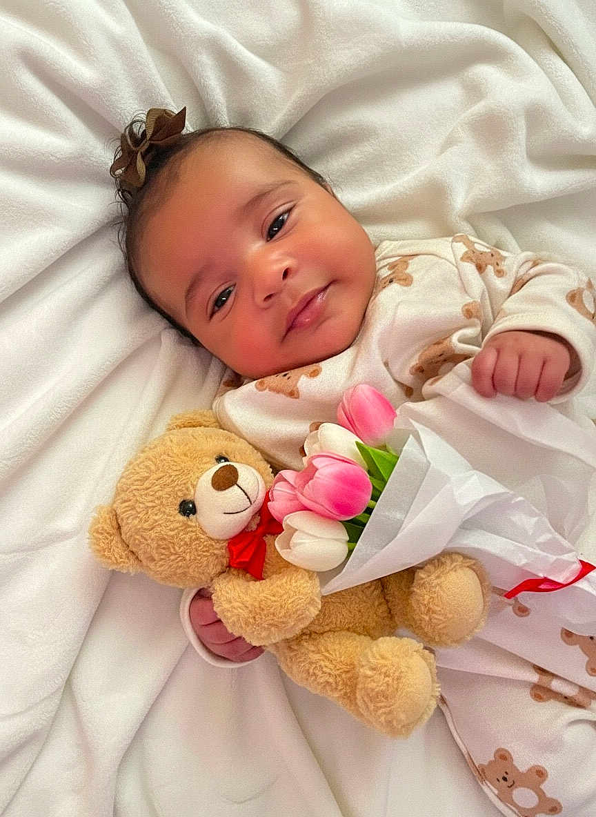 Zionna joined the competition — help win amazing prizes! baby, infant, teddy_bear, tulips, flowers, blanket, onesie, smile, portrait, cute, soft_toy, bow, happy, laying_down, closeup, cozy, hand, bed, plush, nursery