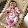 baby, infant, baby_clothing, headband, pink, polka_dot, socks, baby_lounger, cushion, wooden_floor, indoor, cute, portrait, child, person, cozy, soft_fabric, relaxing, small_hands, footwear