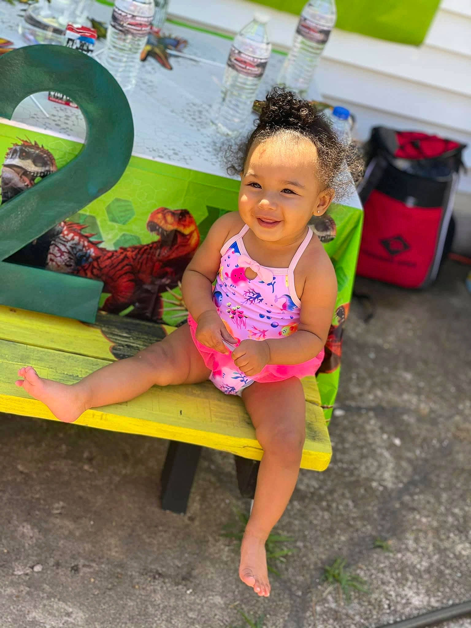 Erin is registered to the contest to win money with this photo: barefoot, child, city, fun, grass, hairstyle, happy, human_leg, joy, leisure, magenta, person, pink, public_space, recreation, sandal, shorts, sitting, smile, summer