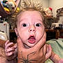 baby, blurred_background, child, expression, face, fingers, furniture, hair, hand, holding, human, indoor, mouth_open, person, room, skin, spider_tattoo, surprised_expression, tattoo, wide_eyes