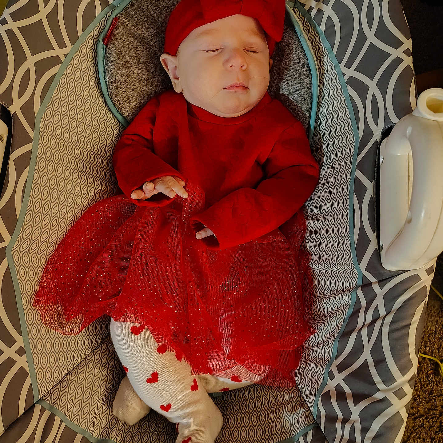 Cecilia is registered to the contest to win money with this photo: adorable, baby, baby_seat, child, comfort, cozy, cute, headband, heart_pattern, indoors, infant, patterned_fabric, peaceful, portrait, red_dress, resting, sleeping, small_hands, soft_lighting, tights