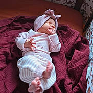 Delaney joined the competition — help win amazing prizes! baby, newborn, infant, child, headband, pink_headband, blanket, maroon_blanket, striped_pants, tiny_toes, hand_in_mouth, sleeping, cozy, soft_light, portrait, couch, fabric, home_interior, adorable, nursery_pattern