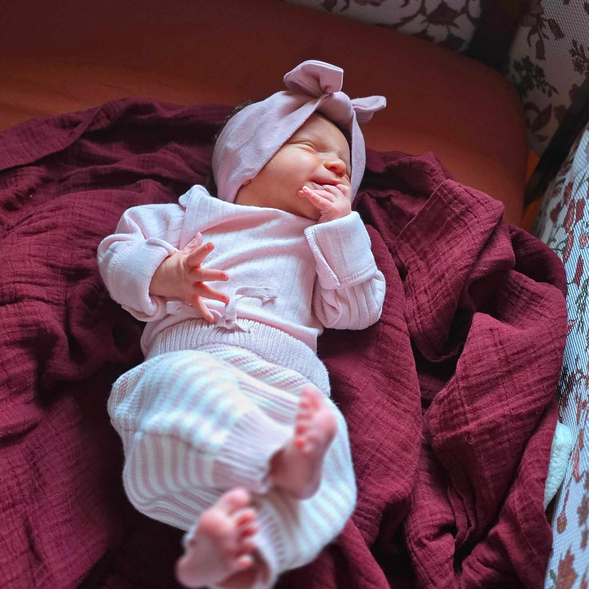 Delaney joined the competition — help win amazing prizes! baby, newborn, infant, child, headband, pink_headband, blanket, maroon_blanket, striped_pants, tiny_toes, hand_in_mouth, sleeping, cozy, soft_light, portrait, couch, fabric, home_interior, adorable, nursery_pattern