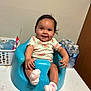baby, basket, blue_baby_seat, child, cute, face, footwear, hand, happy, indoor, infant, person, pink_socks, plastic, room, seated, smiling, table, water_bottles, watermelon_onesie