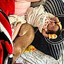 baby, sleeping, mittens, dog, pet, person, hand, ring, blanket, pillow, toy, duck, bed, bedding, pink_shirt, cozy, indoor, resting, snuggling, curled_up