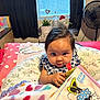 Vada is registered to the contest to win money with this photo: baby, child, infant, book, minnie_mouse, blanket, heart_pattern, pillow, window, blinds, fan, curious, indoor, bedroom, plant, decor, black_hair, clothing, sitting, toy