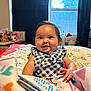 Vada is registered to the contest to win money with this photo: baby, blanket, book, checkered_clothing, child, cozy, curtain, face, furniture, hand, happy, home, indoor, infant, plant, portrait, sitting, smiling, toy, window