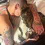 animal, bed, blanket, cat, close_up, comfort, cozy, feline, hand, indoor, kiss_mark, neck, person, pet, relaxation, sleeping, snuggling, tabby_cat, tattoo, white_cat