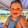 Wesley is registered to the contest to win money with this photo: arm, baby, background, blurred, button, cap, cheerful, child, cute, denim_overall, face, fence, happy, outdoor, portrait, skin, smiling, summer, sunlight, tent