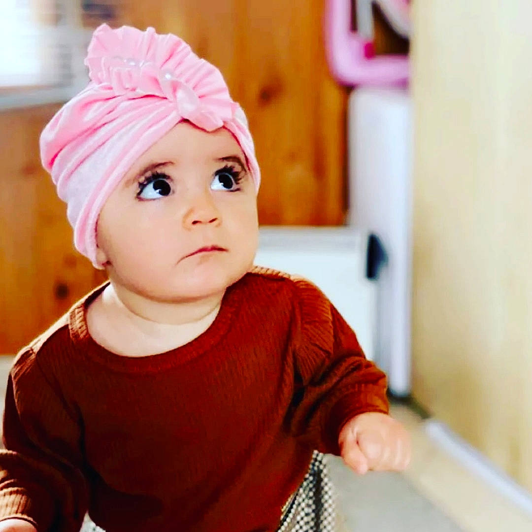 Mercedes participe au concours pour gagner de l'argent avec cette photo : baby, baby_toddler_clothing, cap, cheek, clothing, eyelash, fashion_accessory, fun, happy, headpiece, headwear, knit_cap, lip, magenta, mouth, neck, person, room, sleeve, t_shirt
