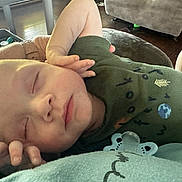 Conan is registered to the contest to win money with this photo: baby, child, closeup, clothing, cute, face, green, hand, human, indoors, infant, newborn, pacifier, peaceful, portrait, relaxing, resting, sleeping, soft_light, toddler